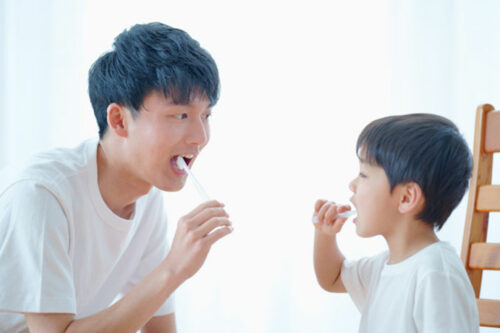 子供の歯磨き習慣を教える父親と楽しそうに磨く男の子のイメージ